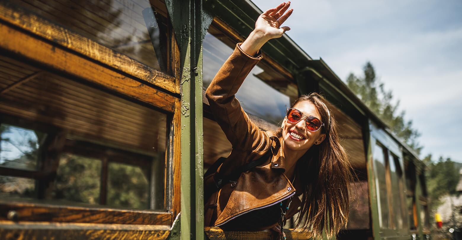 smiling woman waving from the window of a train
